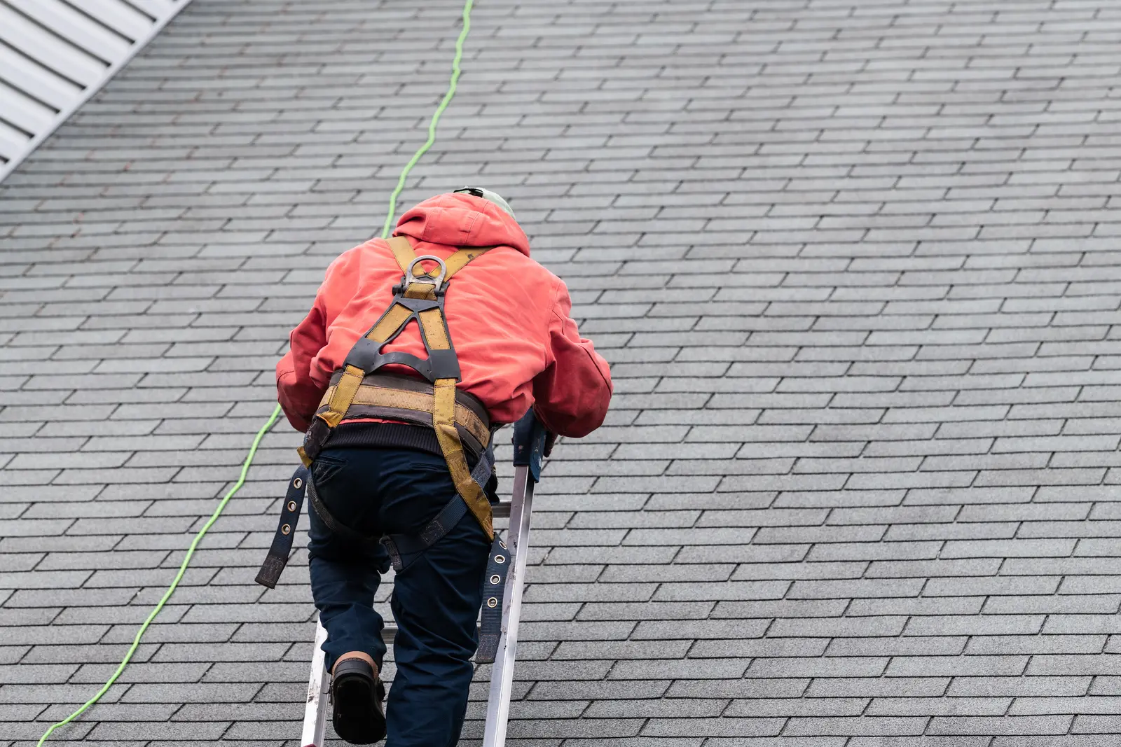 Roofer inspecting a residential roof for leak sources