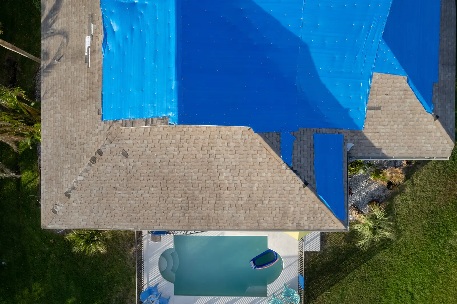 Blue tarp covering a section of storm-damaged roof after high winds
